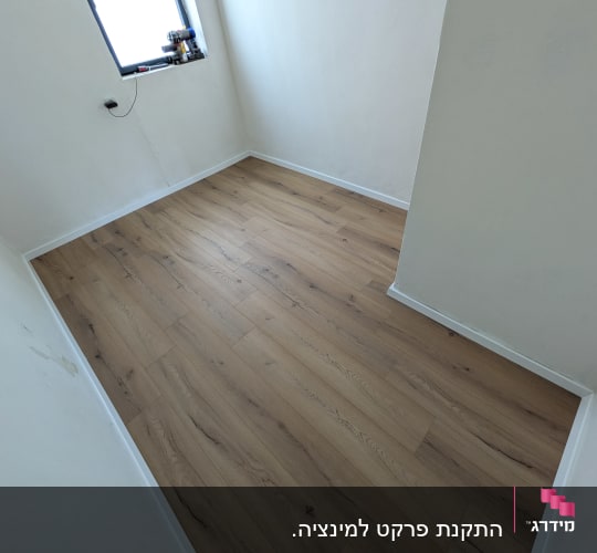 חדר עם רצפת פרקט חדשה וכלים על אדן החלון